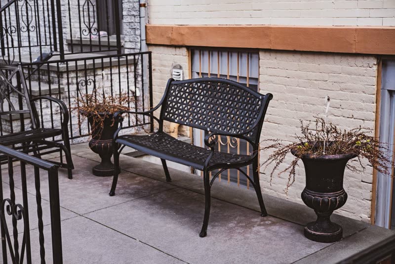 Concrete porch with a wrought-iron bench and planters